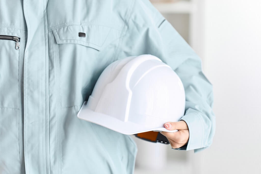 Majstor u ruci drži zaštitni šlem, kao deo zaštitne opreme na svkaom gradilištu ili industrijskom postrojenju