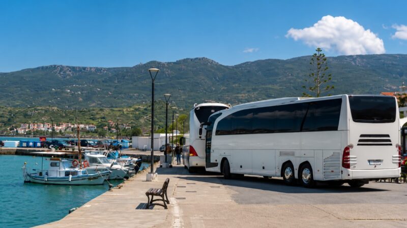Turistički autobusi parkirani pored obale u Grčkoj, prikaz organizovanog autobuskog prevoza do letovališta.